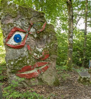 Ein großer Baumstumpf mit einem aufgemalten Gesicht im Wald. Seckach im Odenwald. | © Touristikgemeinschaft Odenwald e.V.