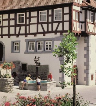 Fachwerkfassade mit Brunnen, in dem sich das Museum befindet | © Touristikgemeinschaft Hohenlohe e. V. | Eva Maria Kraiss